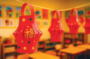 Lanterne chinoise en papier rouge décorée par des enfants pour le Nouvel An chinois, suspendue dans une salle de classe.