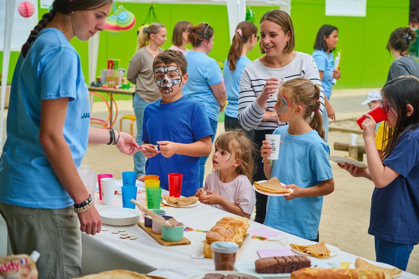 Enfants et parents avec stand de vente de gâteaux et boissons pour financer les projets de l’école