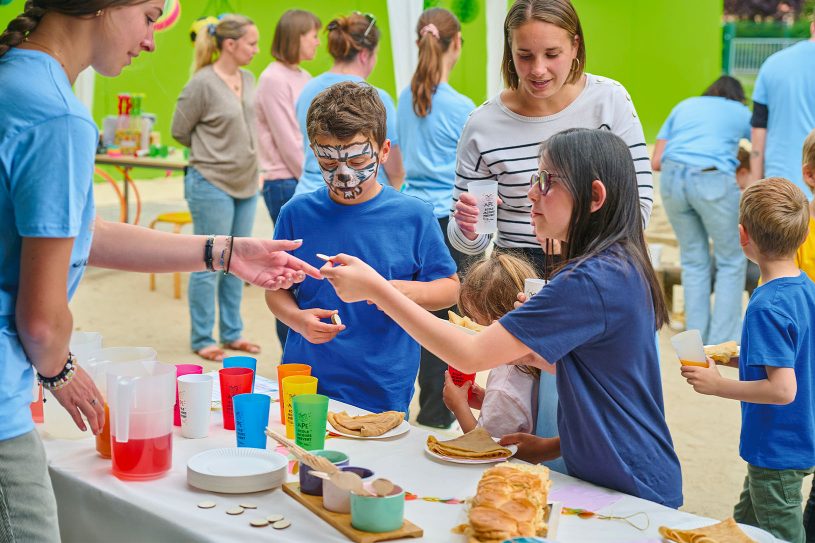 Enfants et parents avec stand de vente de gâteaux et boissons pour financer les projets de l’écol