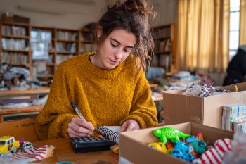 Organisation des lots de kermesse : une bénévole calcule les quantités avec une boîte remplie de jeux